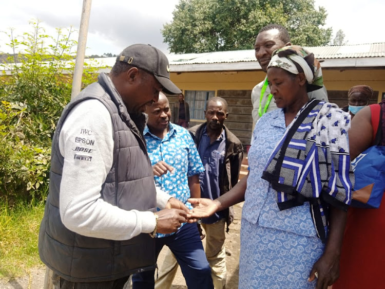 Bahati MP, Kimani Ngunjiri and Independent Senatorial Candidate Crispus Wathimba (in flowered shirt) look at the fingers of a woman whose biometric could not be picked by the KIEMS kit.