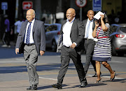 STILL IN CHARGE OF THE COFFERS: Finance Minister Pravin Gordhan and his deputy, Mcebisi Jonas, present a picture of good cheer as they walk from their offices to a court hearing in Pretoria.
