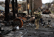 A serviceman uses his mobile phone to film a destroyed Russian tank and armoured vehicles in Bucha, in Kyiv region,