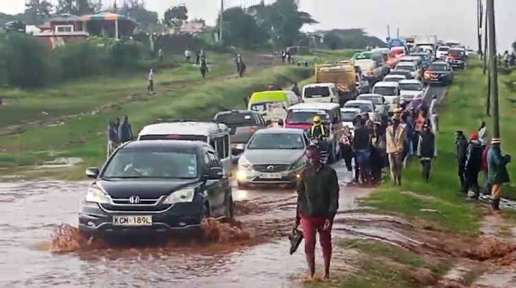 Motorists and pedestrians make a desperate attempt to cross a flooded section of a road in Machakos county after heavy downpour on Monday, April 29, 2024.
