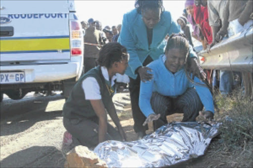 DISASTER: Thuto Itumeleng lies on Main Reef Road near Mohlakeng, Randfontein on the West Rand. District official Onkarabetse Mankuroane comforts Omphemetse Itumeleng and her mother Margaret , the boy's aunt . PHOTO: BAFANA MAHLANGU