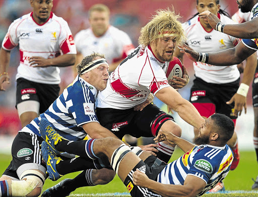 GOLDEN MANE: The Lions' Willie Britz, with ball, takes on Pat Cilliers, left, and Nizaam Carr at Ellis Park yesterday