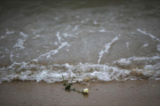 A rose is seen on the beach after being released by Thai children near a wave-shaped tsunami monument for victims of the 2004 tsunami in Ban Nam Khem, a southern fishing village destroyed by the wave December 26, 2014. /REUTERS