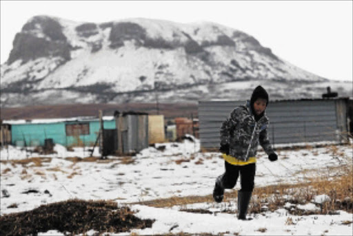 A youth runs through the snow in Intabazwe Township near Harrismith, after the eastern Free State was gripped by cold weather.