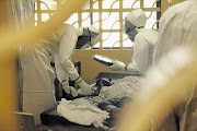 Dr Kent Brantly, left, of the Samaritan's Purse relief organisation, examines Ebola patients at the case management centre at Elwa Hospital, in Monrovia, Liberia. The 33-year-old American doctor has caught the disease.