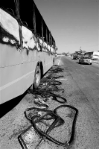 RESULT OF ANGER: Motorists drive past a burnt-out wreckage after commuters torched 30 buses on the Moloto road in KwaMhlanga, near Cullinan, on Monday. Pic. Werner Beukes. 11/08/08. © Sowetan.