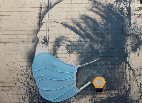 A piece of Banksy street art titled ‘The Girl with the Pierced Eardrum’, adorned with a protective face mask, at Albion Dock in Bristol in the UK, April 23, 2020. Picture: REUTERS/Rebecca Naden