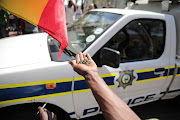 Members of the Rastafarian community celebrates with police nearby, 18 September 2018, at the Constitutional court in Johannesburg, after the court ruled that the private use of marijuana is not a criminal offence. 
