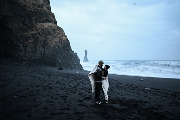 A couple at Reynisfjara, a world-famous black sand beach near Vik, Iceland.