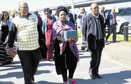 SOMBRE: Shuma Sibeko, daughter of the late Archie Sibeko flanked by the ANC’s veteran’s league deputy president Phil Norushe, left, and president Snuki Zikalala on her arrival at East London airport with her father’s remains Picture: SIBONGILE NGALWA