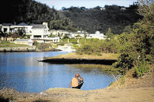 TRAGIC LOSS: A young boy drowned in the Nahoon river on Saturday – his father sits along the banks after police recovered the body Picture: MARK ANDREWS