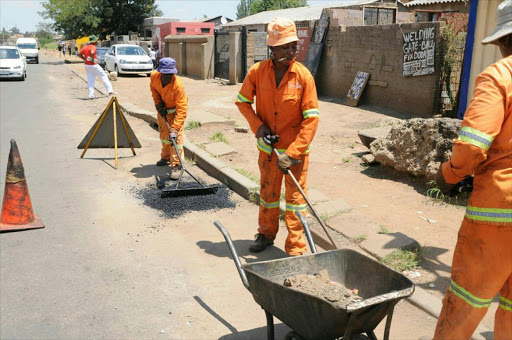 Municipal construction workers patching up the potholes in Zola North, Soweto