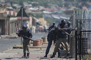 Police fire rubber bullets while being pelted by rocks by protesters, in October 2018, in Westbury, Johannesburg. 