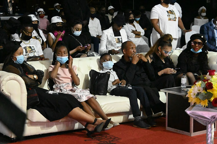 Mshoza's family members, including her two children, sit on a couch at the memorial service.