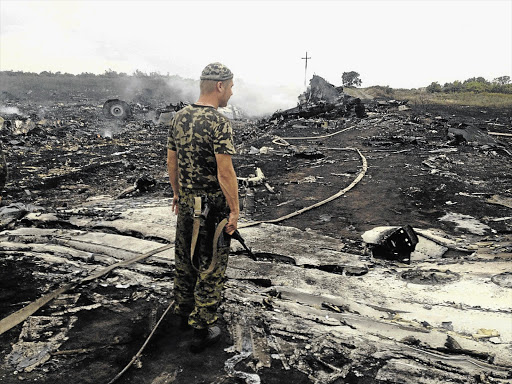 DEVASTATION: A pro-Russian separatist at the site of a Malaysia Airlines plane crash in the settlement of Grabovo in the Donetsk region yesterday