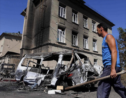 A man walks past vehicles destroyed during the recent shelling in the eastern Ukrainian town of Ilovaysk. Picture Credit: Reuters