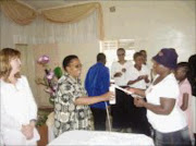 LET THERE BE LIGHT: Pastor Alice Thulare, middle, helps a member of the Senkosi Caregiver group light a candle to mark the start of 'Celebrating Life' by people living and affected by HIV-Aids held at the Pentecostal Holiness Church in Daveyton at the weekend. Pic. Dan Fuphe. 17/12/07. © Sowetan.