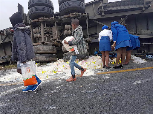 TAKING ADVANTAGE : A truck carrying grocery items was looted after it overturned on the N6 near AmaBhele village on Sunday Picture: FACEBOOK