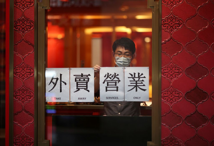 A man wearing a face mask displays a sign for takeaway services at an eatery on March 24 2020 after New South Wales began shutting down non-essential businesses and moving toward harsh penalties to enforce self-isolation as the spread of the coronavirus reached a "critical stage" in Sydney, Australia.