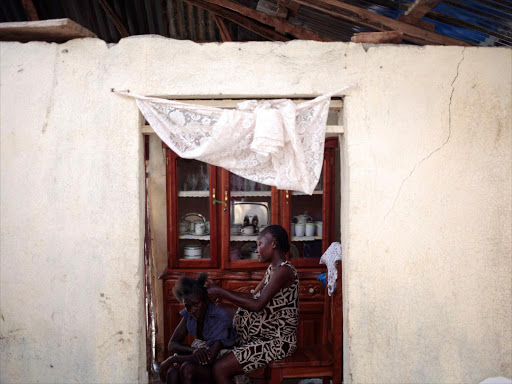 A woman combs the hair of another woman in a house affected by Hurricane Matthew in Damassins, Haiti, October 22, 2016. /REUTERS