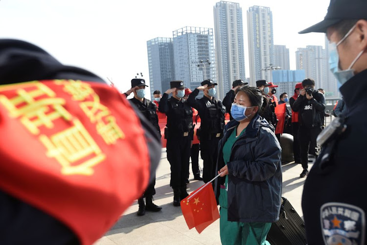 Police officers salute as a medical worker arrives at the Wuhan Railway Station before leaving the epicentre of the novel coronavirus disease outbreak, in Hubei province, China, on March 17 2020.