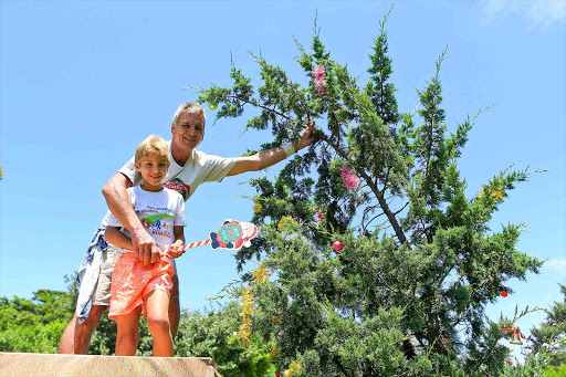 MERRY MEN: Quigney handyman Joe de Vries and his son Liam are the mystery Christmas elves who decorated a tree alongside Nahoon Reef Drive with baubles, tinsel and old clothes for the needy Picture: STEPHANIE LLOYD
