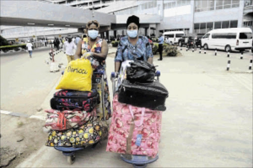 DANGEROUS TIMES: Passengers arriving at the Lagos airport wear face masks and gloves photo: AFP