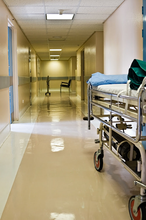 Empty hospital corridor, waiting chairs and bed