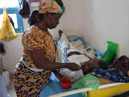 Jemimah Koli feeds her sick husband Stephen Ndambuki at the Kitui Level 4 Hospital yesterday. The doctors’ and nurses’ strike started countrywide /MUSEMBI NZENGU