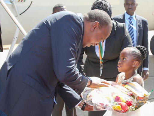 President Uhuru Kenyatta receives a bouquet of flowers from a flower girl on arrival in Lusaka, Zambia for the 2016 African Development Bank annual meeting on Tuesday May 24, 2016. Photo/PSCU