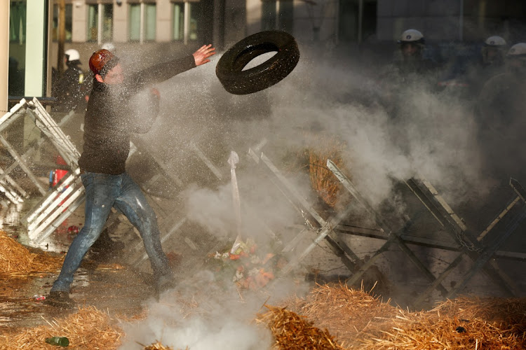 A demonstrator throws a tyre over a barricade during a protest by farmers from Belgium and other European countries near the European parliament over price pressures, taxes and green regulation, on the day of an EU summit in Brussels, Belgium February 1 2024. Picture: YVES HERMAN/REUTERS