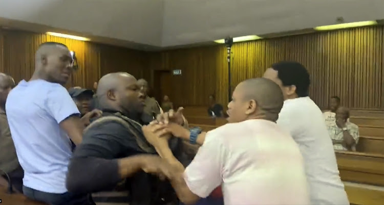 Correctional services warden Enerst Jele is manhandled by three accused in the Senzo Meyiwa case – Mthobisi Mncube, Mthokoziseni Maphisa and Fisokuhle Ntuli – in court on Monday.