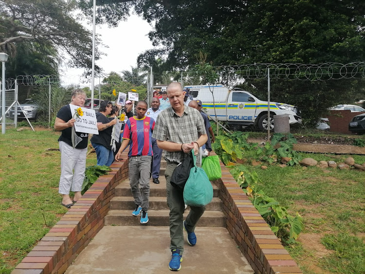 Protesters line the entrance to the Amanztimtoti magistrate's court as Werner de Jager, who is accused of murdering his wife, pastor Liezel de Jager, walks past.