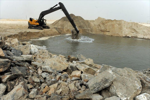 A caterpillar digs reclaimed land from the sea, on January 31, 2013 in Lagos, during the building of the three and a half kilometre long sea defence barrier called "The Great Wall of Lagos" built to shield from coastal erosion Eko Atlantic, a new city born from the Altantic ocean in Lagos.