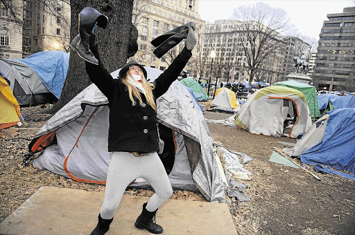 Protester Emily Margaret retrieves her boots from her tent as US National Park Service police cordon off the Occupy DC encampment in McPherson Square in Washington on Saturday Picture: JONATHAN ERNST/GALLO IMAGES