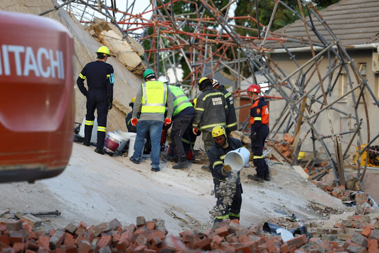 Rescue workers remove rubble from the site where construction workers are trapped under a building that collapsed in George on Monday