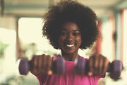 A fitness fanatic works out in a gym with dumbbells.