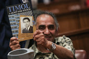 Ahmed Timol’s Brother, Mohammed holds out a book written by Imtiaz Cajee, Timols Nephew ahead of the judgment into his death at the North Gauteng High Court in Pretoria. Timol died after falling from the 10th floor of John Foster Square in 1971 while being detained. / Alaister Russell