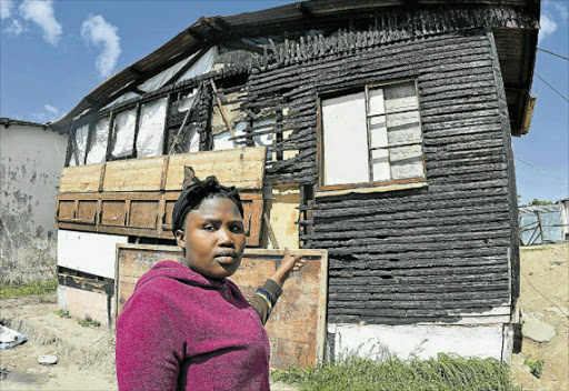 DESPERATE: Siphokazi Ngonwana, 24, of Duncan Village points at the remains of her mother’s house that survived the blaze on July 1. Her family of ten are appealing for assistance from government for a new house to be built Picture: RANDELL ROSKRUGE