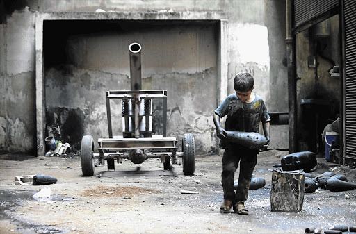 Issa, 10, carries a mortar shell in a weapons factory run by the Free Syrian Army, in Aleppo. Issa works with his father in the factory for 10 hours every day except Fridays