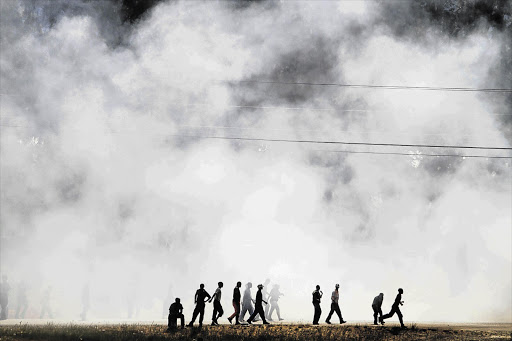 Farmworkers run through the smoke of fires set throughout the town of Wolseley, near Ceres, Western Cape. File photo.