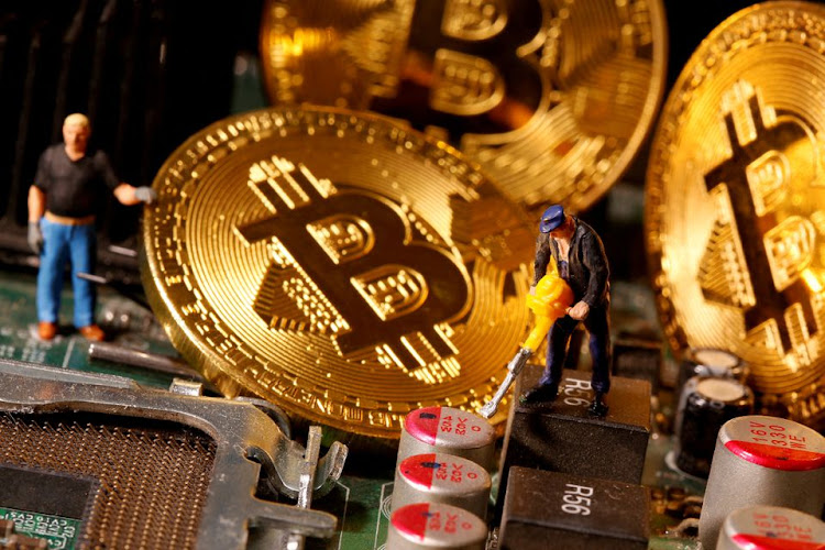 A representation of virtual currency Bitcoin and small toy figures are placed on computer motherboard in this illustration taken January 7, 2021.