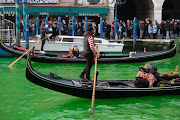 People ride in boats as waters of Grand Canal turned green after a protest by 'Extinction Rebellion' climate activists in Venice, Italy, December 9, 2023. 