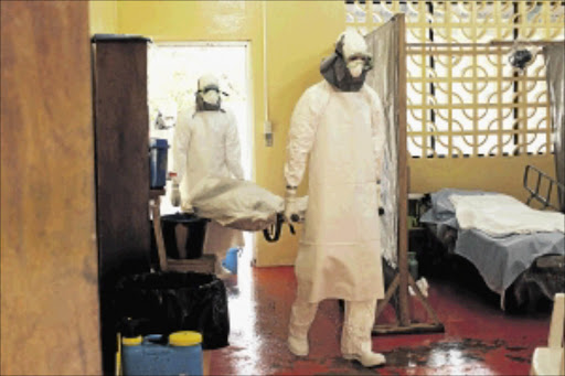 danger: Two people in protective clothing carry a body at an ebola isolation ward at a hospital outside Monrovia Photo: Samaritans Purse/Getty Images