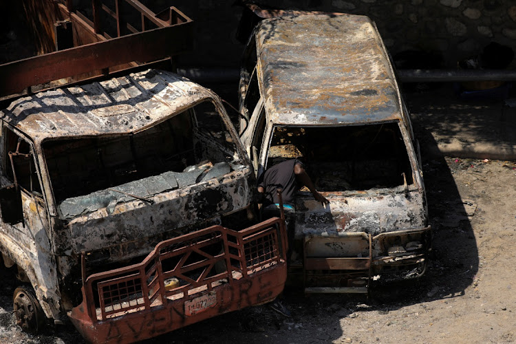 A man looks inside one of the vehicles that was set on fire by armed gangs on Monday night outside the Carrefour de l’Aeroport sub-police station of the Haitian National Police, in Port-au-Prince, Haiti on Tuesday. Picture: REUTERS/RALPH TEDY EROL