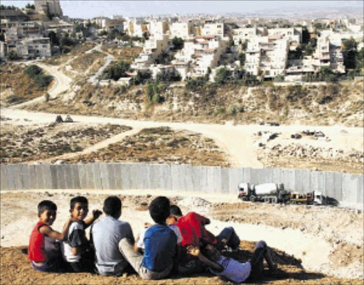 APARTHEID WALL: Children of the Shu'fat refugee camp in Jerusalem look at the Israeli Wall and Pisgat Amir settlement. PHOTO: Anne Paq