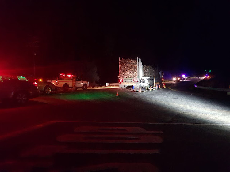 The wreckage of a car lies wedged beneath a timber truck on the R617 near Underberg. Seven people were killed in the accident.