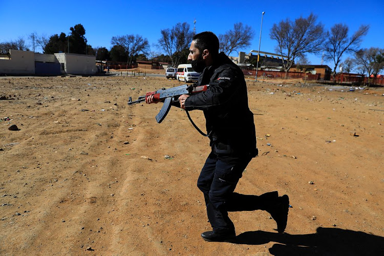 A private security member helps police officers and soldiers restore law and order in Soweto on July 13, 2021.