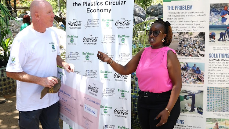 Watamu Marine Association project manager Steve Trot receives a cheque for Sh7.2 million from Coca-Cola Foundation's Pauline Mwaura to buy a recycling machine and PPE that will help fight plastic pollution and create jobs for more than 500 youth and women, September 17, 2022.