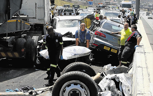 HORROR PRANG: A body is removed from the wreckage yesterday. At least four people were killed and scores injured in the pile-up near the N12's Voortrekker Road offramp.